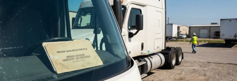 Driver Qualification File folder visible on semi-truck dashboard at commercial trucking yard